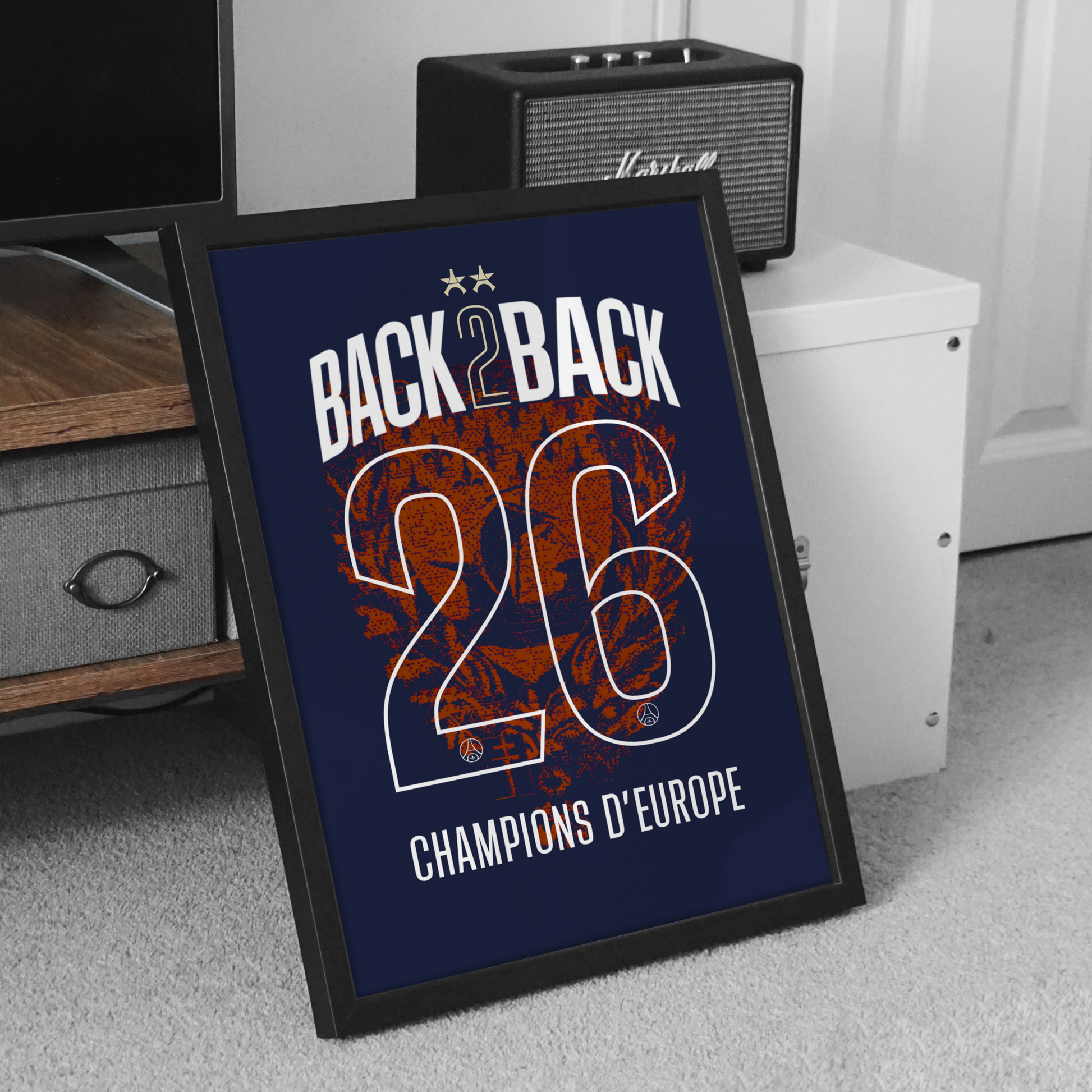 Cadre Maillot PSG Back 2 Back 2026 posé au sol avec affiche collector bleu marine et rouge