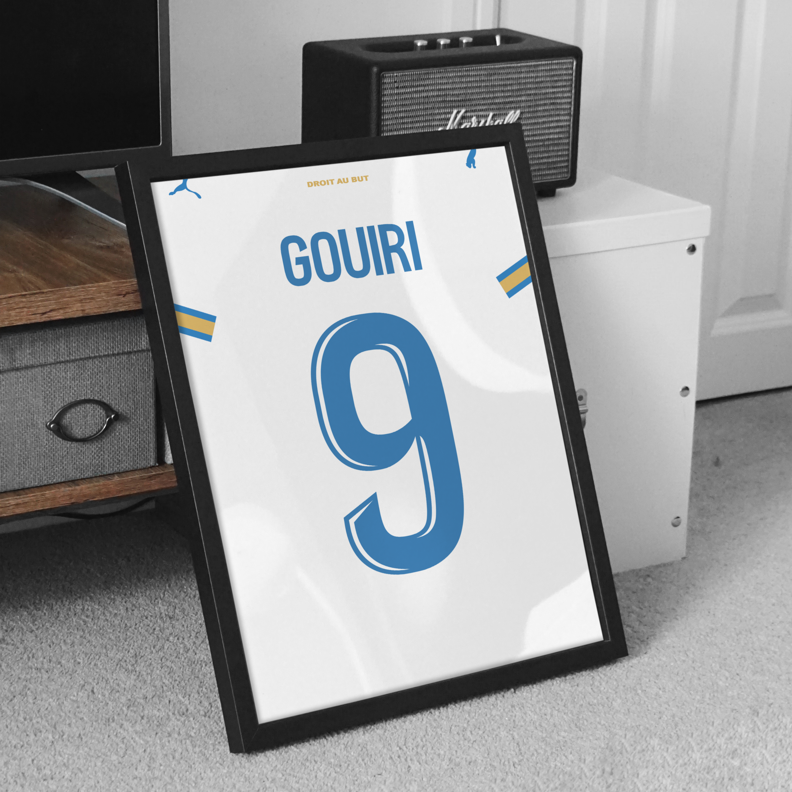 Cadre maillot OM domicile 2026-2027 Gouiri 9 posé au sol dans un intérieur moderne